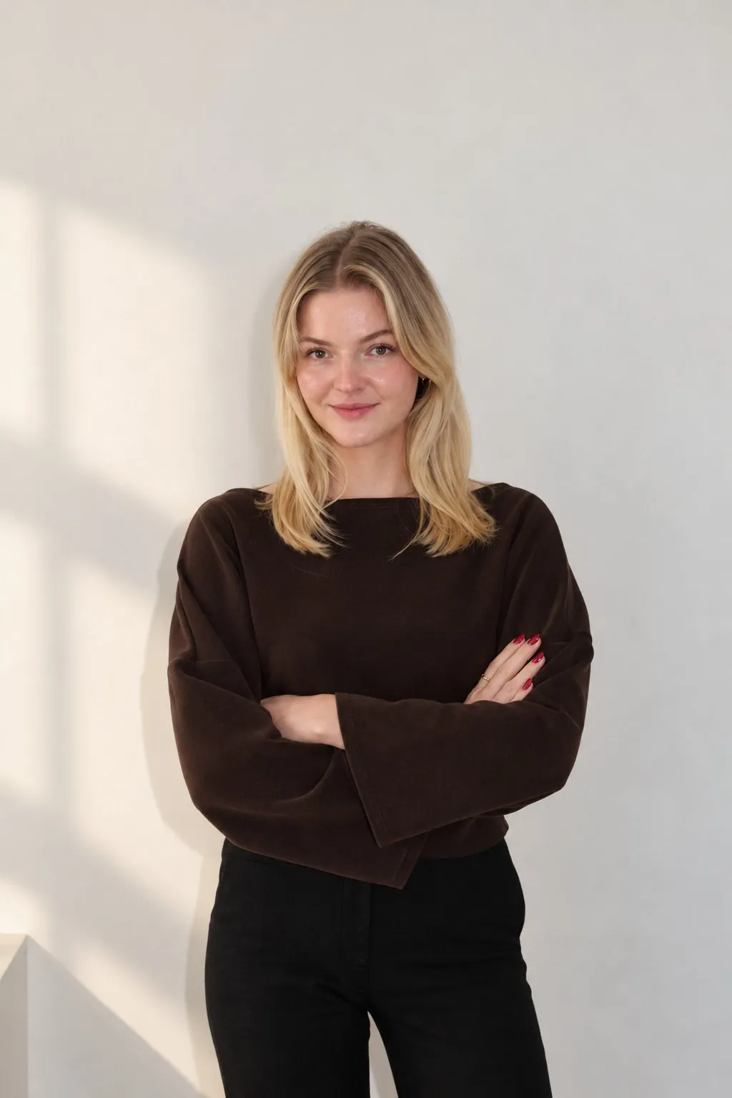 Emily von scrollwert. mit verschränkten Armen vor einer hellen Wand